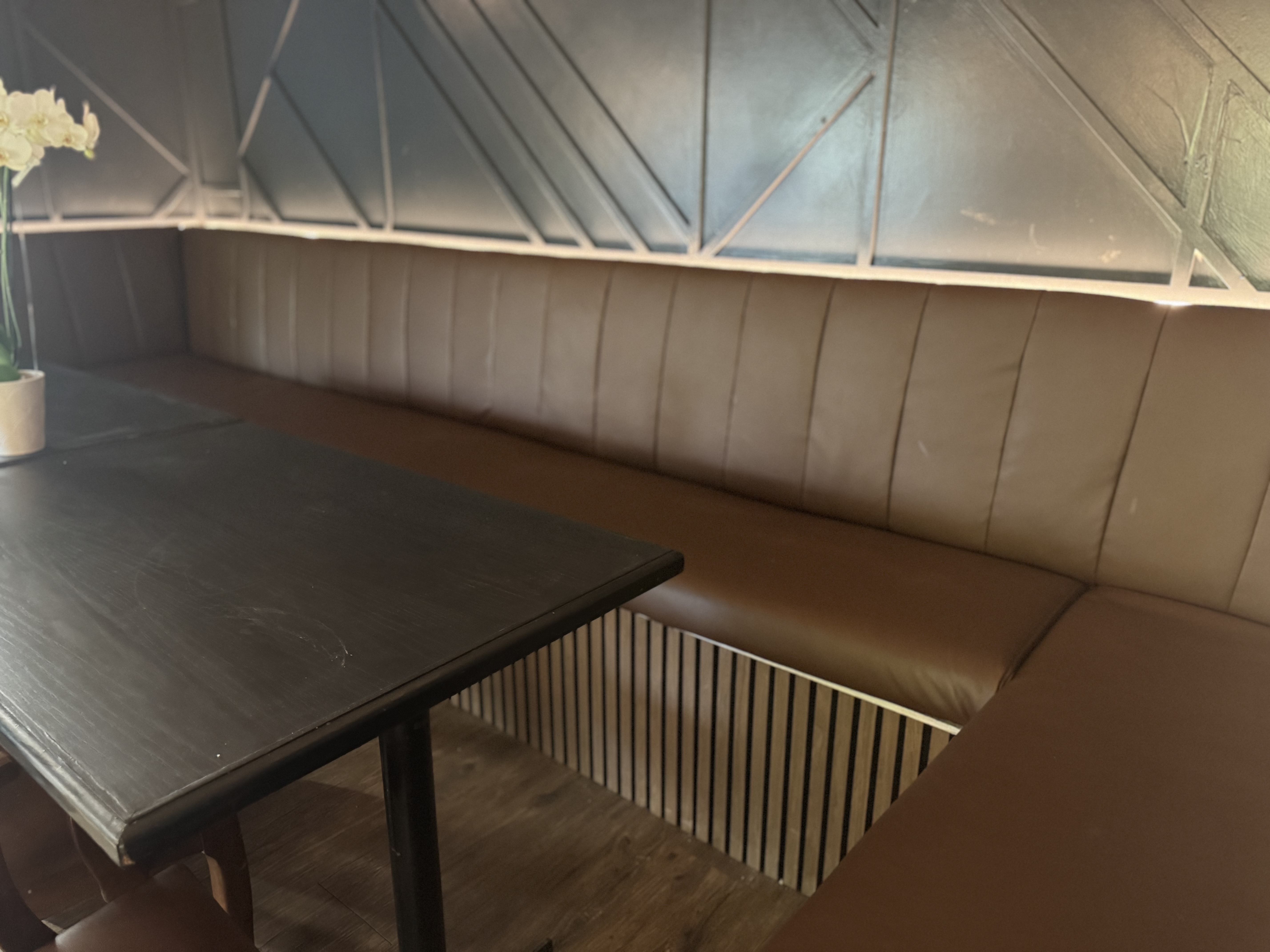Dark channel-tufted booth with orchid on table